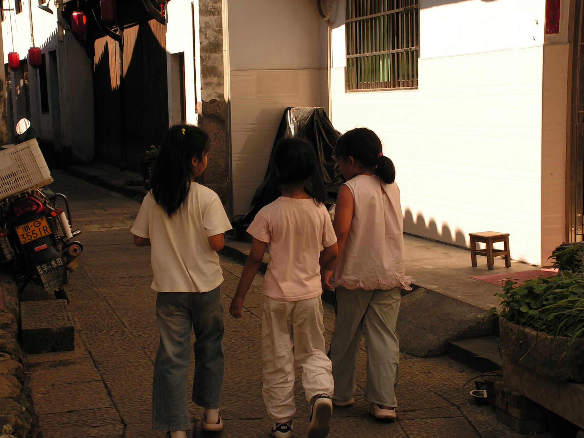 三个孩子结伴走过老街巷道