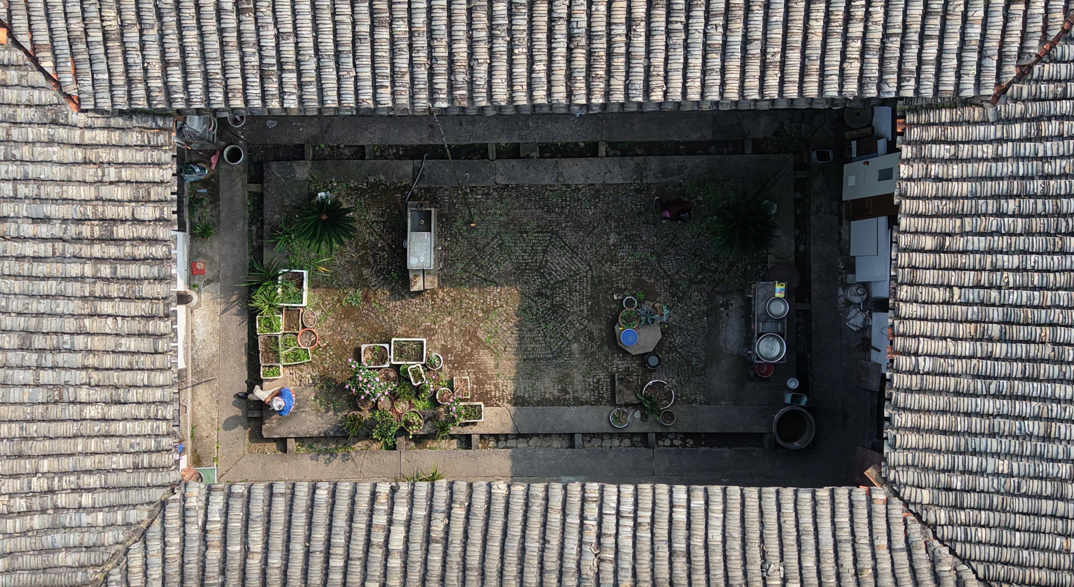 从空中俯视荣华堂天井，屋瓦围合着花盆、水槽和生活器皿