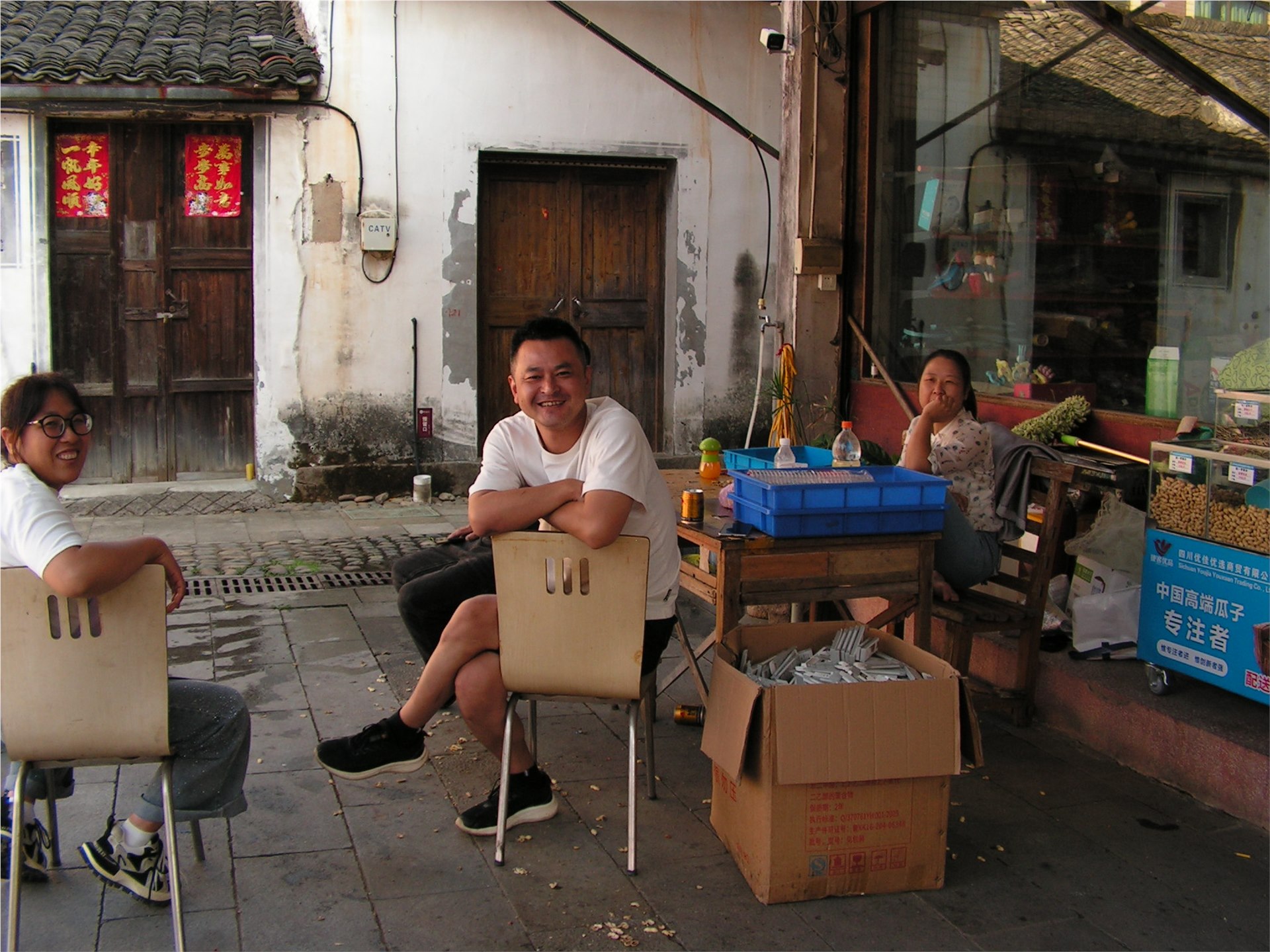 三个人坐在沿街小店前休息交谈