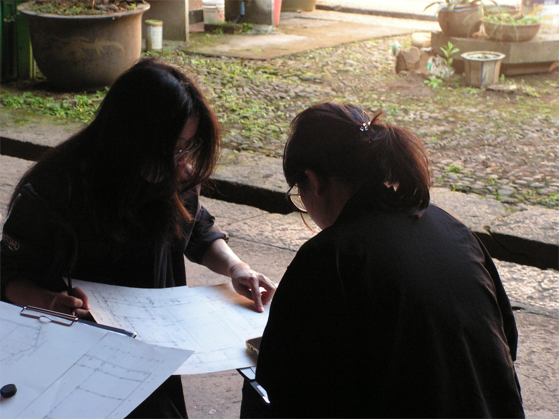 两位学生在天井里对照图纸讨论测绘修改